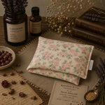 Load image into Gallery viewer, Floral-patterned heat pillow with herbs and books on a wooden surface
