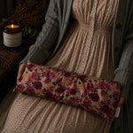 Load image into Gallery viewer, Person holding a floral lupin heat pillow with a candle and plant in the background
