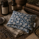 Load image into Gallery viewer, Floral-patterned heat pillow on a wooden surface with herbs and books in the background
