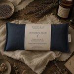 Load image into Gallery viewer, Lavender eye pillow with label on a wooden surface with dried lavender and essential oils.
