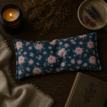 Load image into Gallery viewer, Floral-patterned eye pillow on a wooden surface with a candle and dried lavender.

