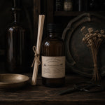 Load image into Gallery viewer, Vintage-style bottle with label and reed diffuser on a dark wooden surface
