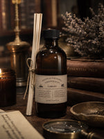Load image into Gallery viewer, Bottle of Chandler &amp; Co. Library perfume with reed diffuser on a wooden surface with books and decorative items.
