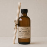 Load image into Gallery viewer, Brown bottle christmas reed diffuser with black cap and white label on a beige background
