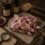 Load image into Gallery viewer, Floral fabric heat pillow on a wooden surface with herbs and books
