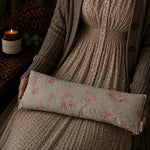 Load image into Gallery viewer, Person holding a floral lupin heat pillow with a candle and decorative elements in the background
