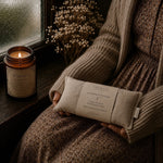 Load image into Gallery viewer, Person holding a lavender linen eye pillow next to a lit candle on a windowsill - handmade in Australia - karsten &amp; Co.
