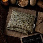 Load image into Gallery viewer, Floral-patterned fabric heat pillow on a wooden surface with candles and jars in the background

