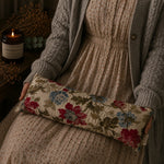 Load image into Gallery viewer, Person holding a floral lupin heat pillow with a candle and decorative elements in the background
