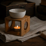 Load image into Gallery viewer, wooden oil burner on a wooden block with a lit candle inside, on a textured surface.
