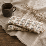 Load image into Gallery viewer, Floral eye pillow on a textured fabric surface with a mug and dried flowers - Karstenadco
