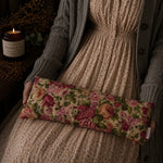 Load image into Gallery viewer, Person holding a floral lupin heat pillow with a candle and decorative elements in the background
