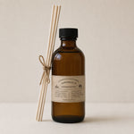 Load image into Gallery viewer, Brown bottle reed diffuser with black cap and wooden sticks on a beige background
