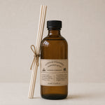 Load image into Gallery viewer, Brown bottle reed diffuser with label and white sticks on a beige background
